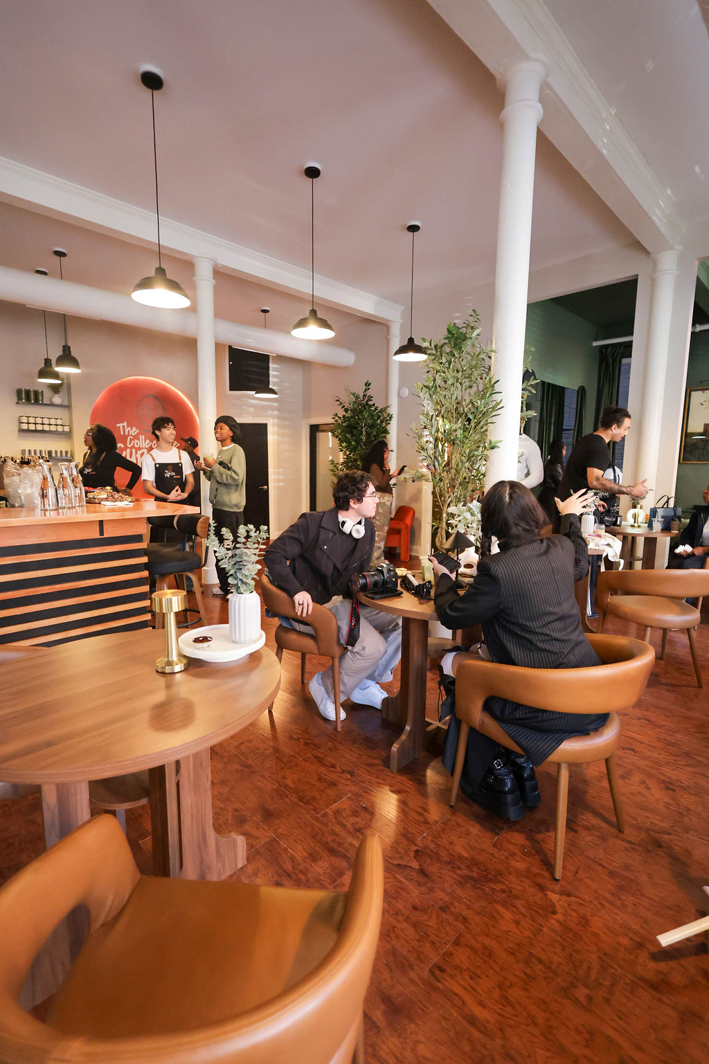 Guests and team members across the main floor, with wooden tables, leather chairs and the counter beyond